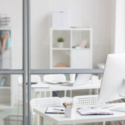 Designer workplace in office near transparent noteboard and accountant working behind it